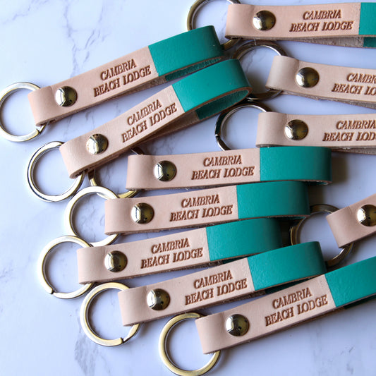 Multiple leather keychains with custom engraving, displayed on a light surface.